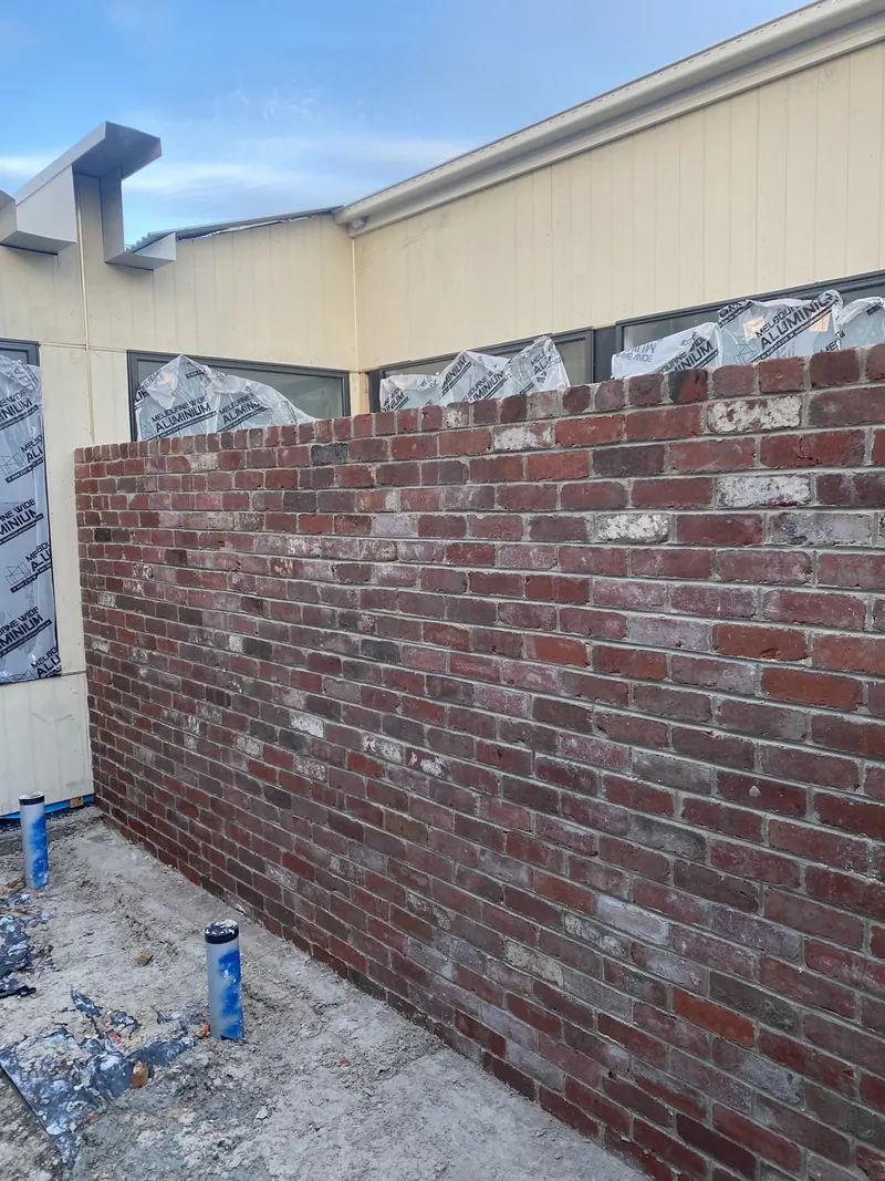 Red brick feature wall beside a light-coloured home
