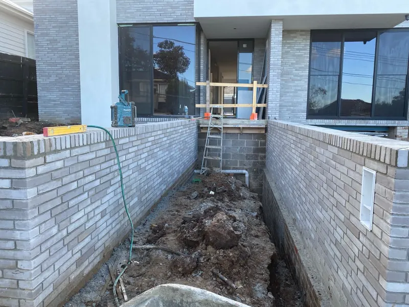 Light brick walls lining a lightwell beside a modern home