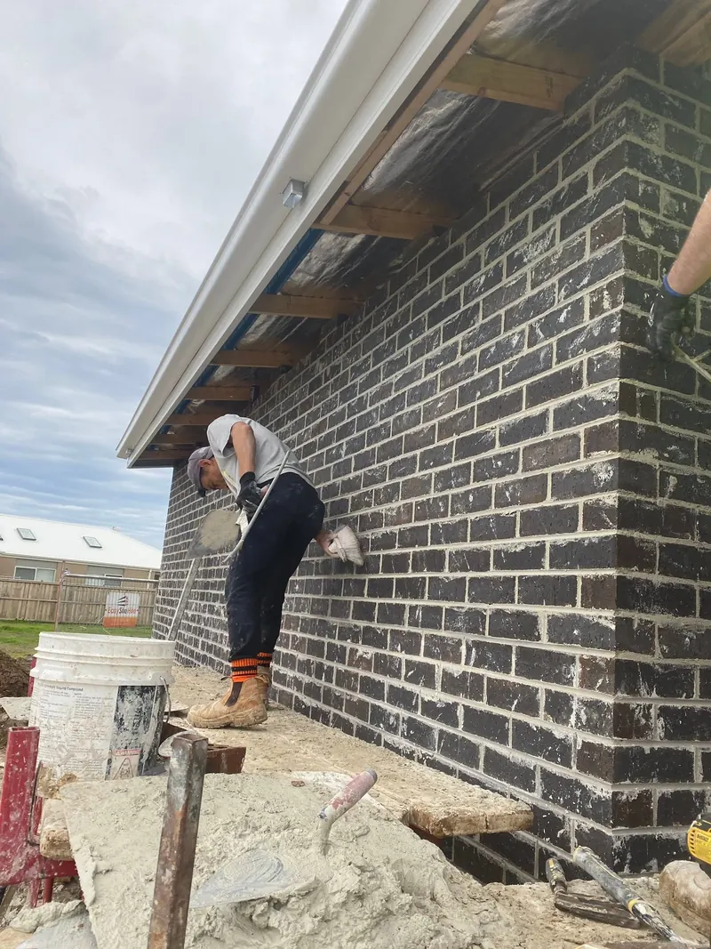 Pointing the joints on a dark brick wall